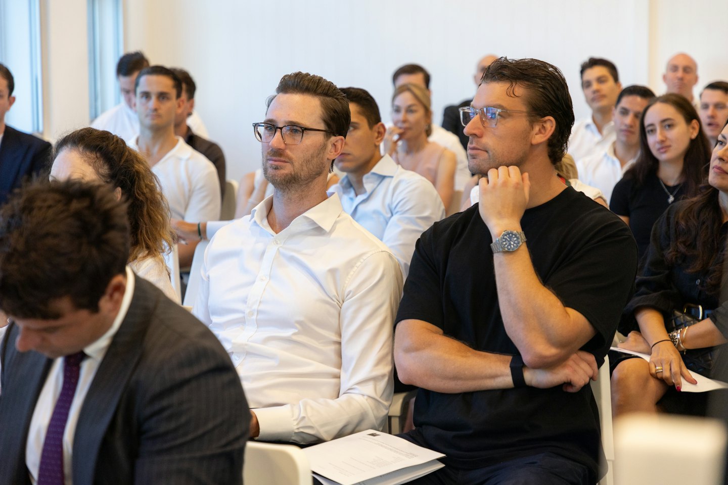 Diverse professionals listen at a modern corporate event.